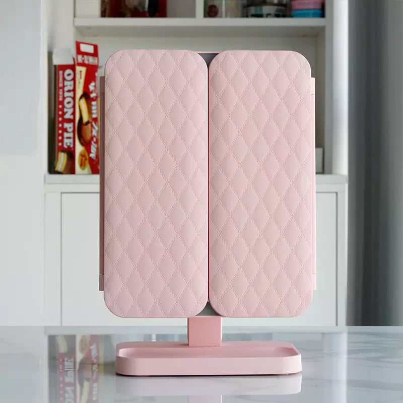 Pink LED makeup mirror with quilted double cover folded shut on pedestal base
