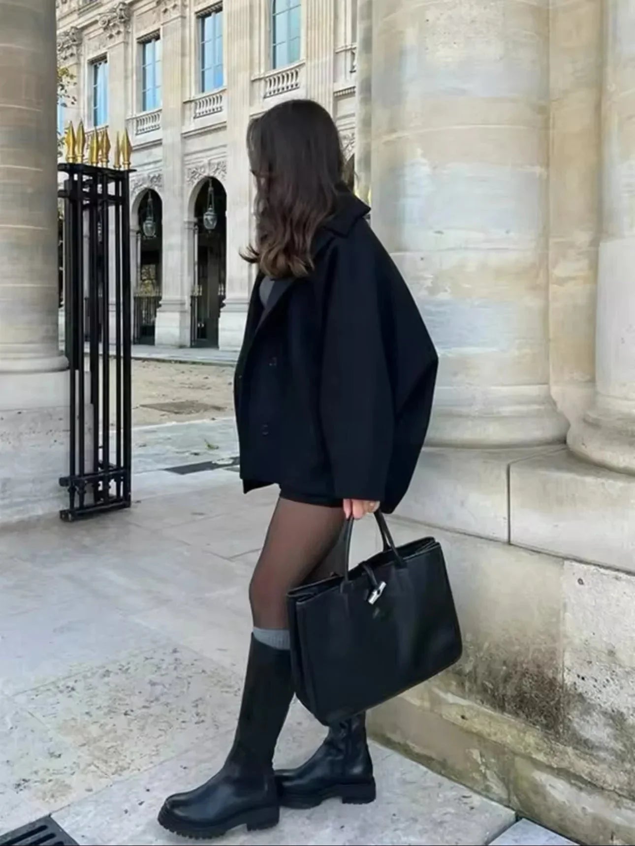 Black loose-fit women’s coat with large lapels and button front, side view.