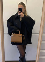 Black loose-fit women’s coat with large lapels and button front, mirror selfie.