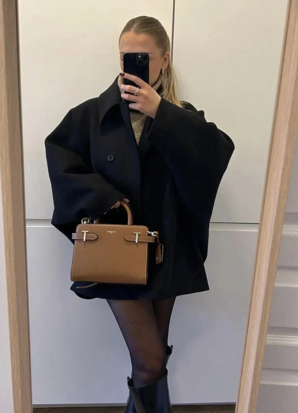 Black loose-fit women’s coat with large lapels and button front, mirror selfie.