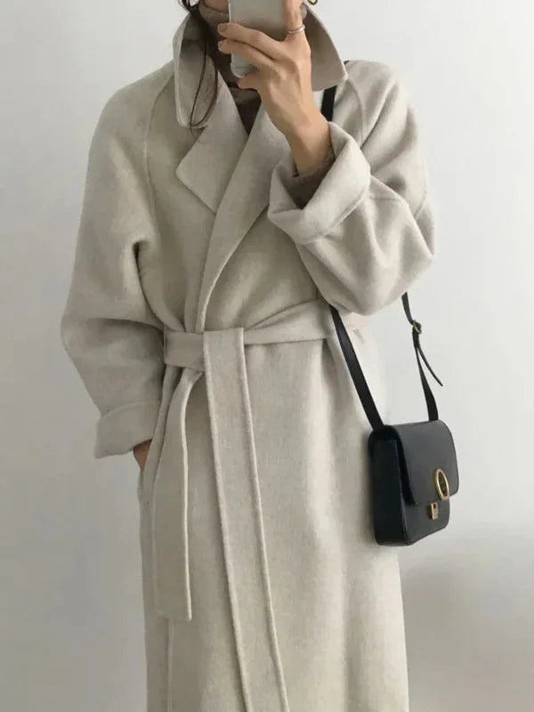 Long women's coat with waist belt and notched collar, light gray, front view