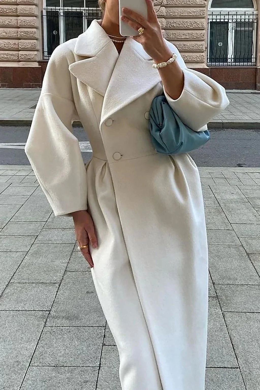 Women’s long white coat with wide collar, structured shoulders, buttoned front