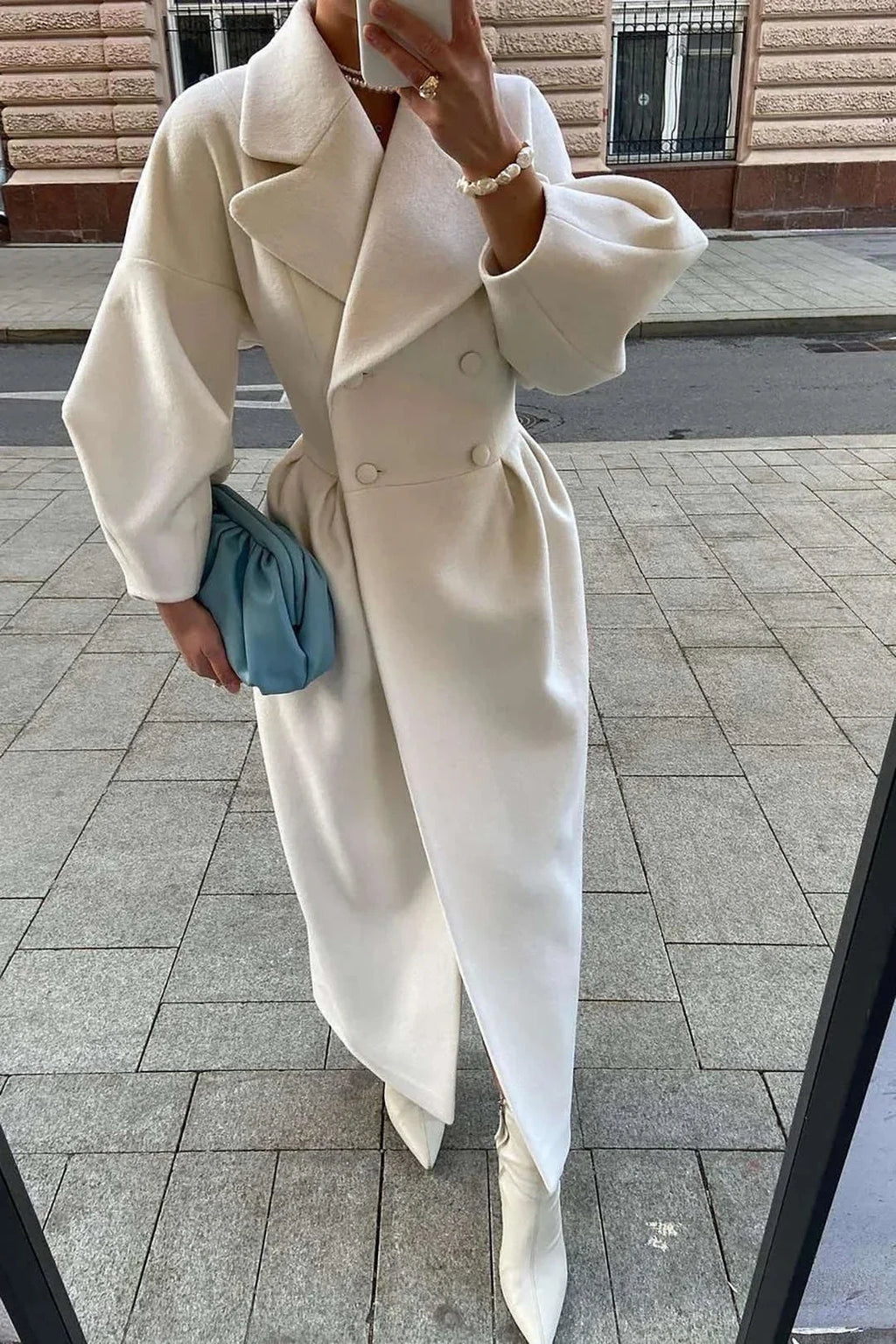 Women’s long white coat with wide notched collar, double-breasted buttons, belted waist