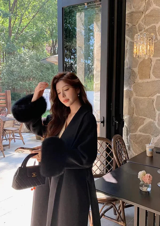 Long belted women’s coat with faux fur sleeves, black wrap V-neck