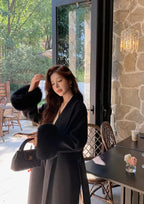 Long belted women’s coat with faux fur sleeves, black wrap V-neck