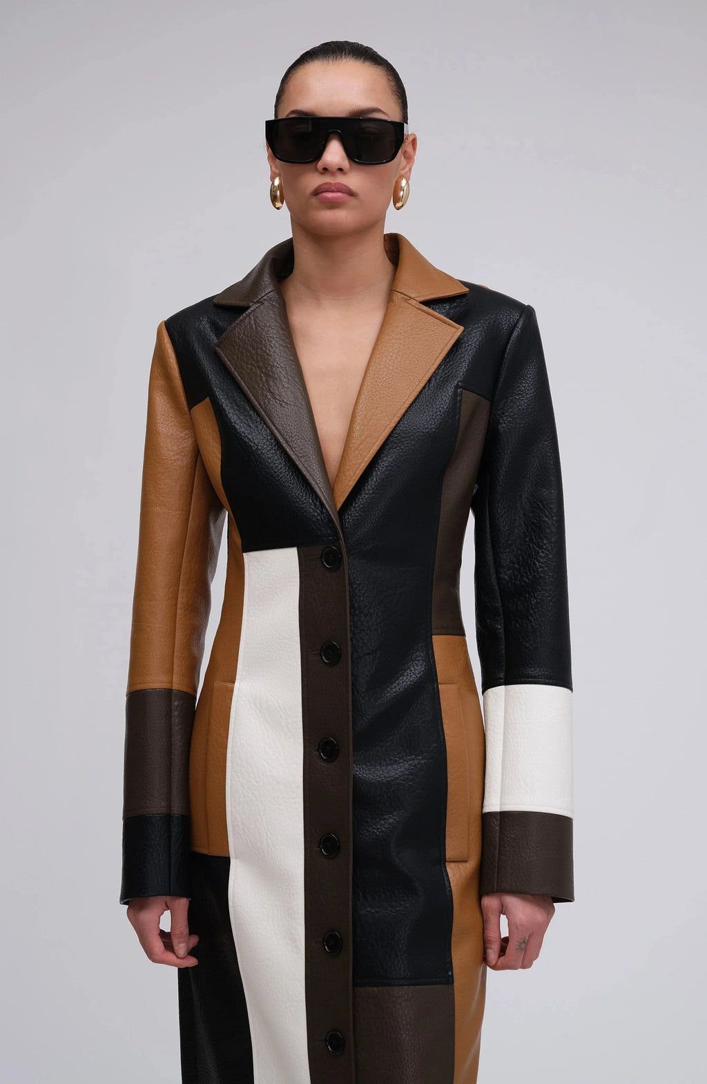Long patchwork coat with notched lapels, black buttons, and brown/white color blocks.