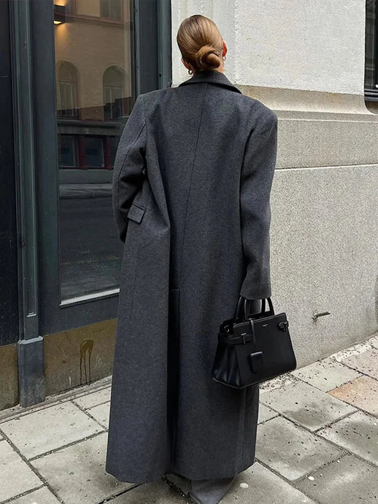 Women’s long coat, dark gray, back view with wide lapels and buttoned sleeve cuffs