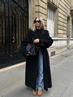 Women's long black belted coat with wide lapels and button front