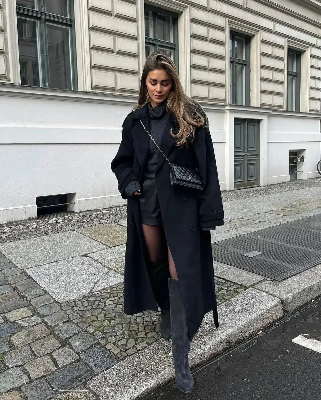 Women's long black belted coat with wide lapels and button front, side view