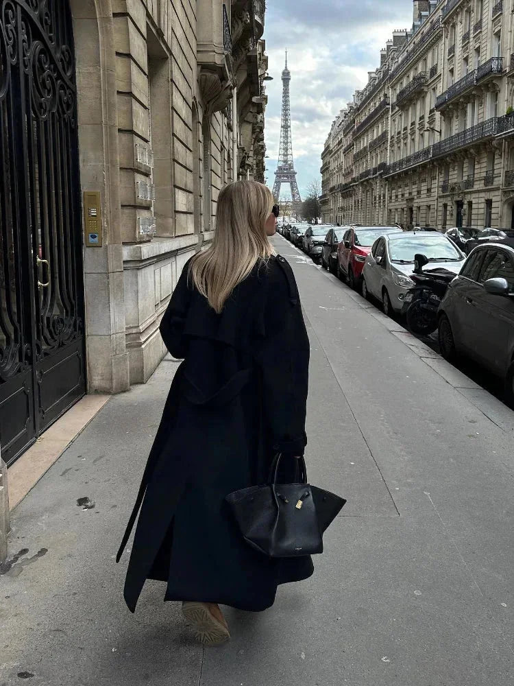 Back view of women's long black belted coat with wide lapels