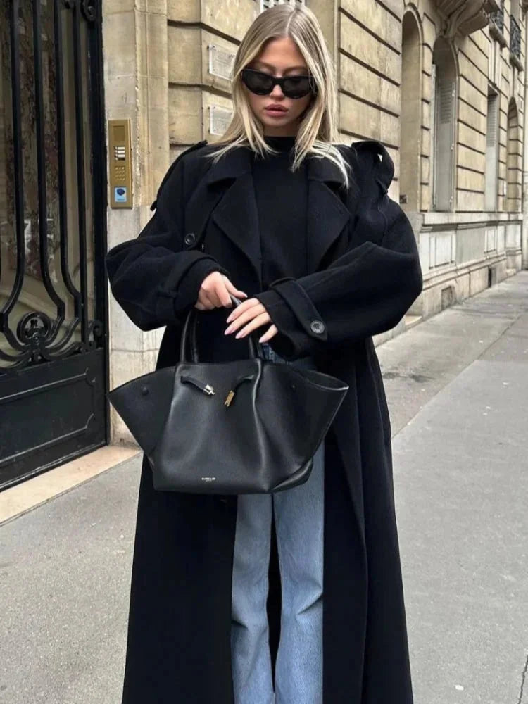 Women's long black belted coat with wide lapels, button front, and oversized sleeves