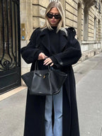 Women's long black belted coat with wide lapels, button front, and oversized sleeves