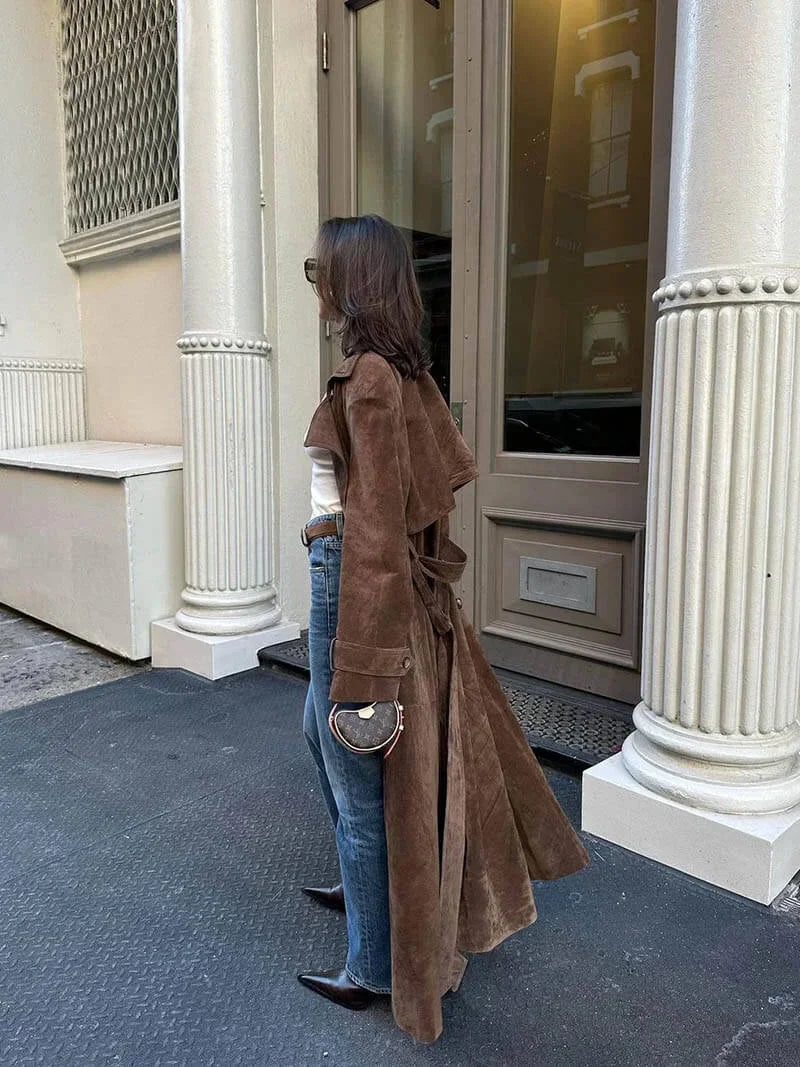 Brown womens trench coat with lapels and belt, side view over jeans