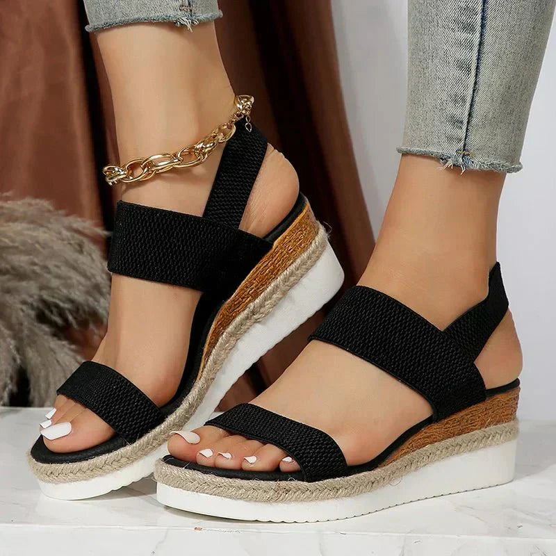 Black platform sandals with textured elastic crisscross straps and open toe, wedge sole