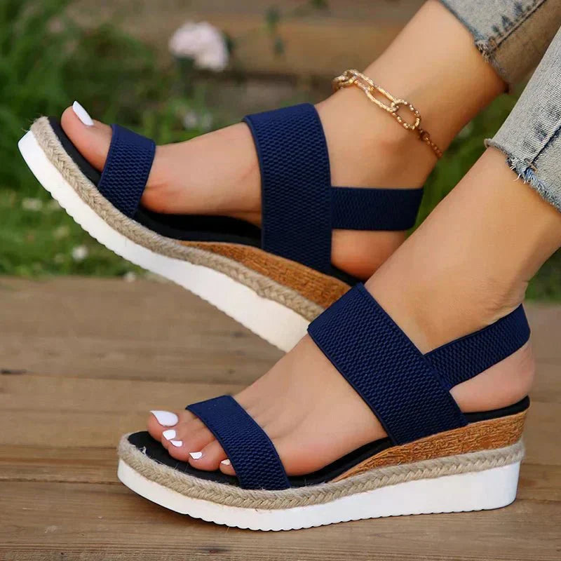 Navy blue platform sandals with elastic crisscross straps, open toe, chain ankle detail