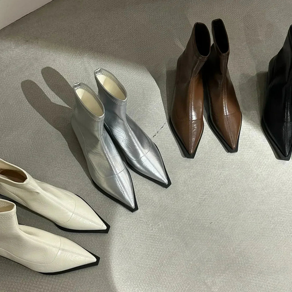 Set of pointed-toe ankle boots in silver, cream, and dark brown on display