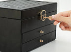 Black leather jewelry box with quilted lid, gold lock, and two pull-out drawers