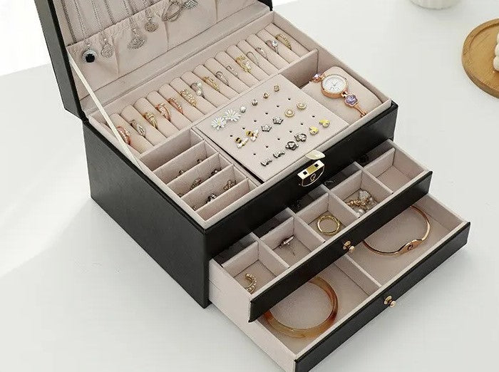 Black multilayer leather jewelry box open with ring holders, earring slots, and drawers