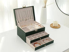 Green leather jewelry box open with necklace slots and drawer compartments