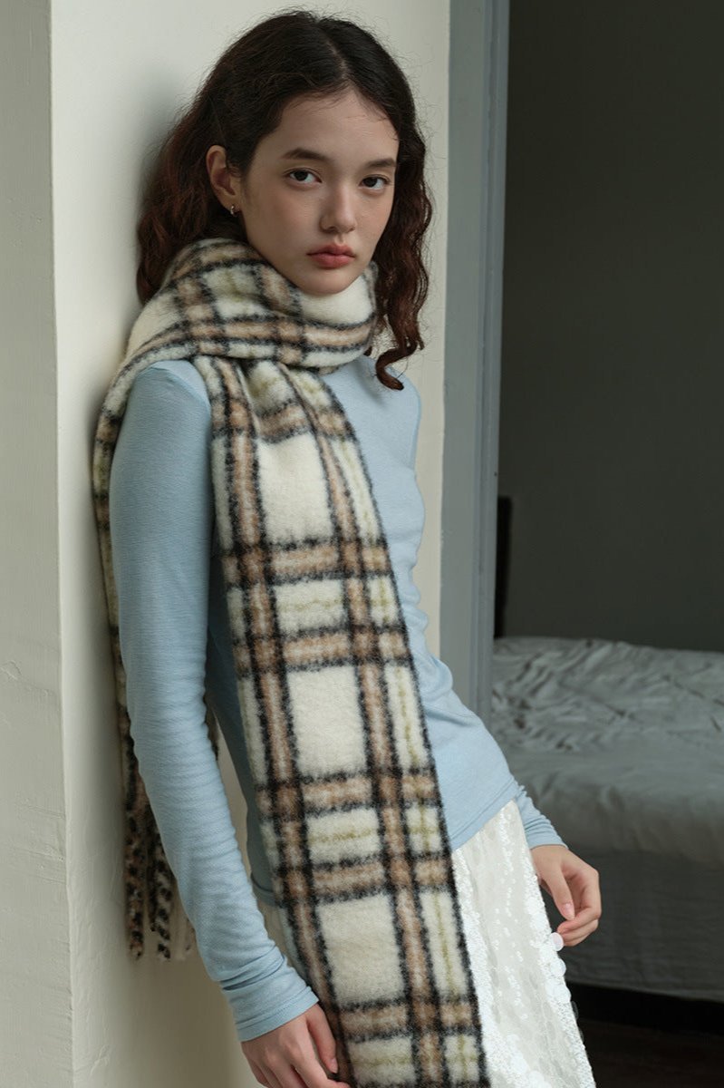 Plaid wool scarf draped on shoulders, off-white with dark lines and fringes