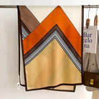 Oversized scarf in orange and tan with black striped chevron V design
