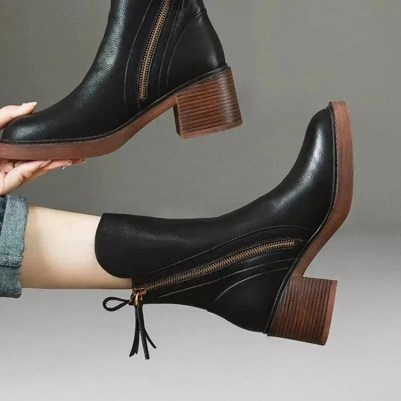 Women’s black leather heeled booties with side zipper and tassel pull detail on block heel.