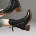 Women’s black leather heeled booties with side zipper and tassel pull detail on block heel.