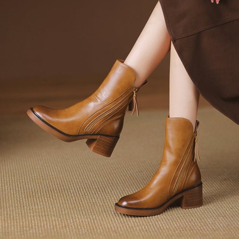 Women’s heeled block-heel booties in tan leather with side zipper and tassel pull.