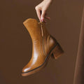 Women’s tan leather heeled booties with side zipper and tassel pull, stacked block heel.