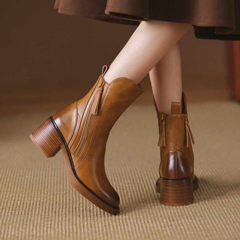 Women’s tan leather heeled booties with side zipper, tassel pulls, and chunky block heel.