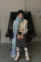 Light blue gradient knit scarf with striped trim and long fringed ends