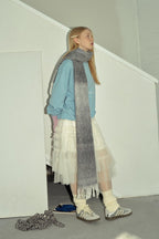 Charcoal gray gradient knit scarf with long fringe ends, draped as a long wrap