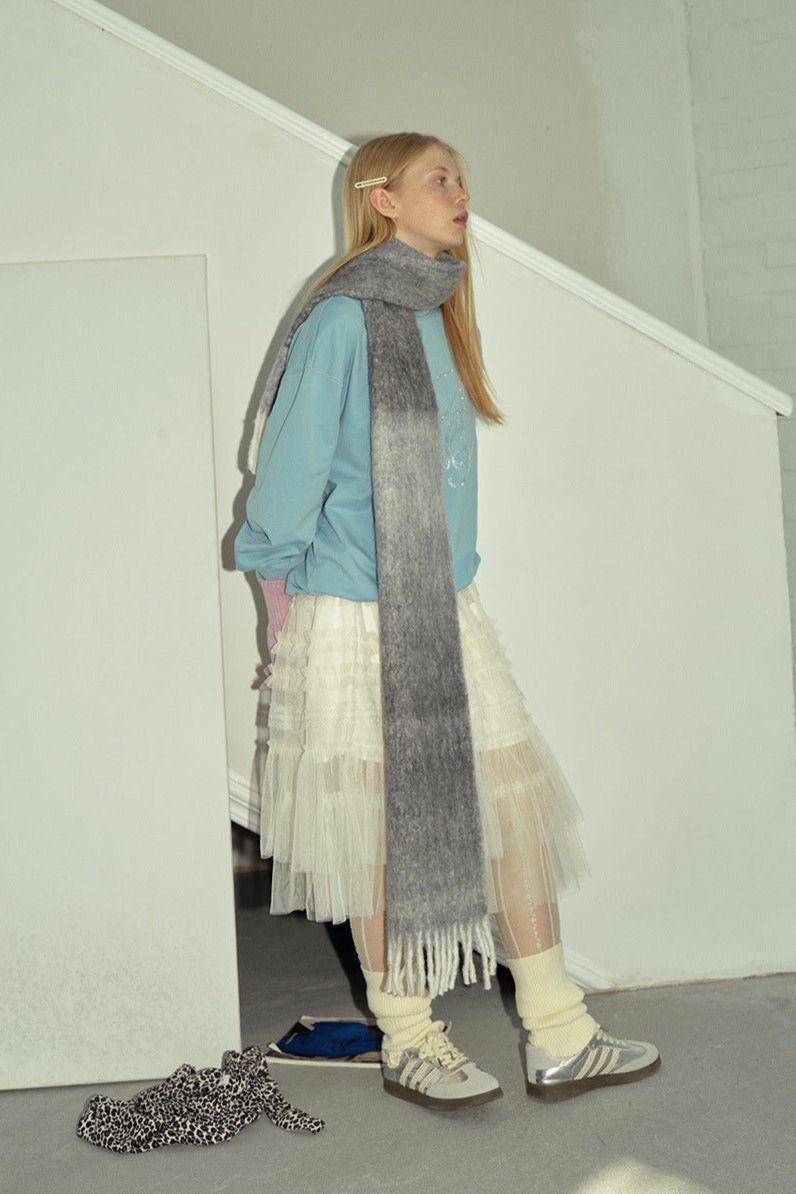 Charcoal gray gradient knit scarf with long fringe ends, draped as a long wrap