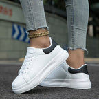 White lace-up trainers with thick sole, black heel collar, side angle with jeans