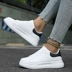 White lace-up trainers with thick sole, black heel panel, worn with jeans
