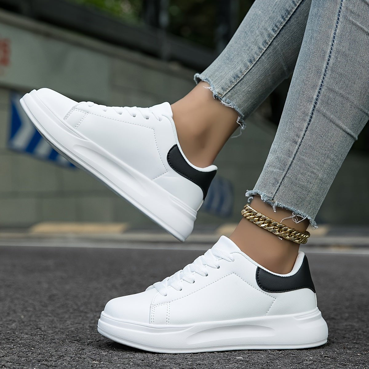 White lace-up trainers with thick sole, black heel panel, worn with jeans