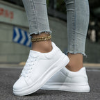 White lace-up trainers with thick sole, smooth toe and black collar trim, side view