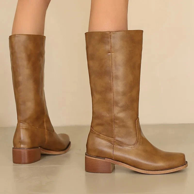 Tan knee-high riding boots with pull-on shaft seam and stacked low heel