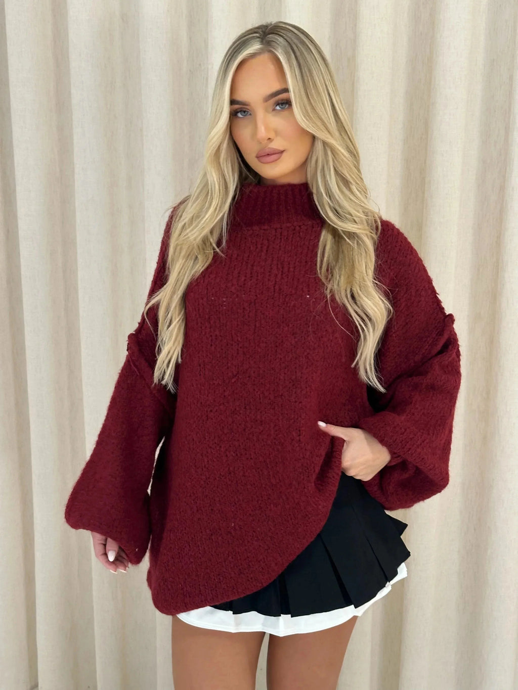 Burgundy loose knit turtleneck sweater with wide cuffs and draped hem