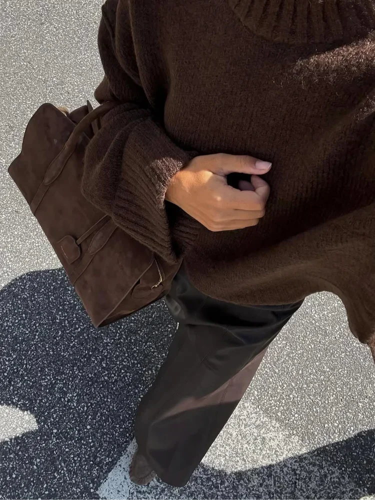 Brown loose knit sweater sleeve; ribbed cuff and textured knit detail near hand