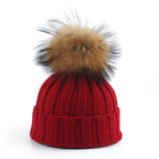 Knit beanie hat with tan pom-pom, ribbed texture, deep red color