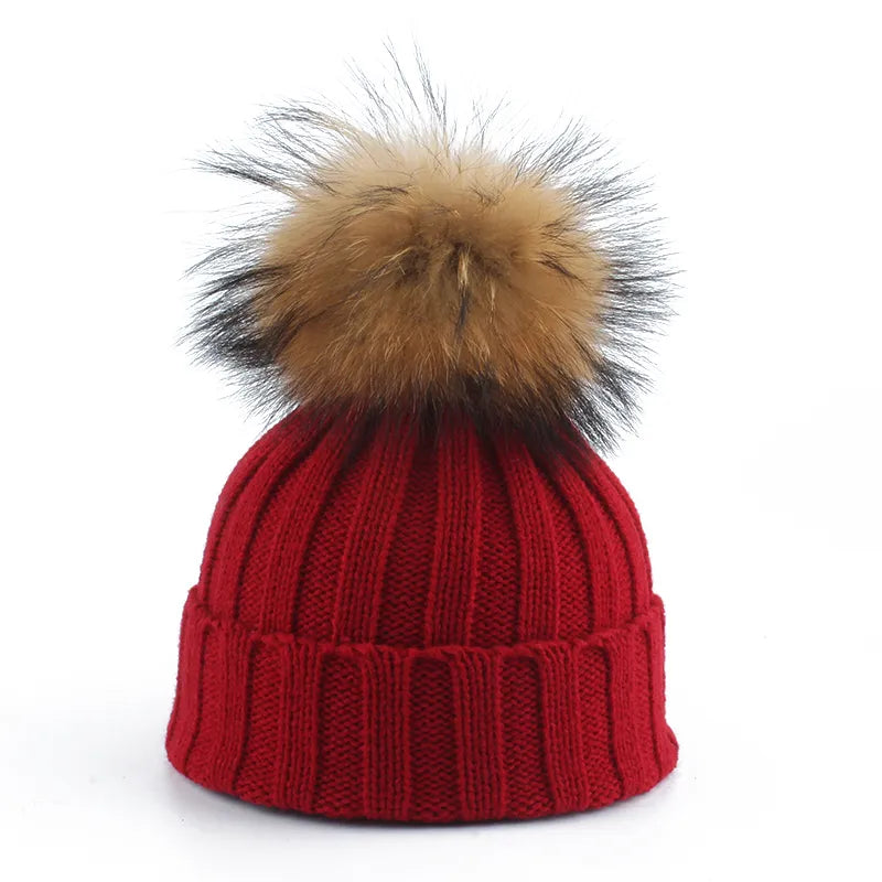 Knit beanie hat with tan pom-pom, ribbed texture, deep red color