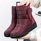 Women's burgundy quilted mid-calf boots with buckle strap, held by hand