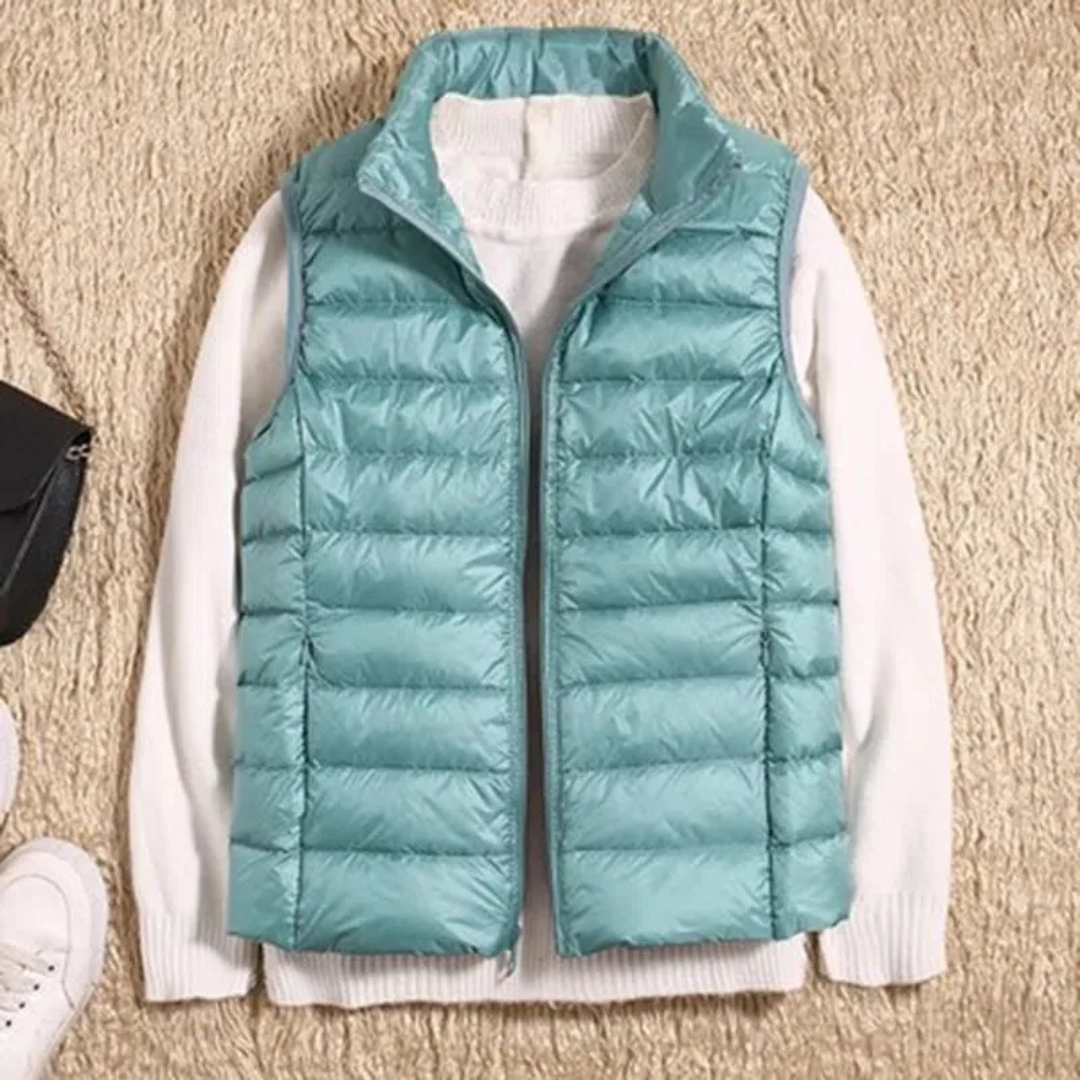 Teal quilted bodywarmer vest with full-zip and stand collar over white sleeves