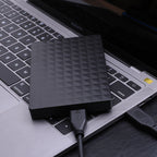 Ultra-thin portable hard drive with black geometric surface and connected USB cable