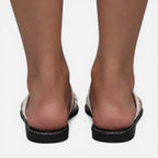 Women’s white flat sandals from the back view with black sole and stitched edge