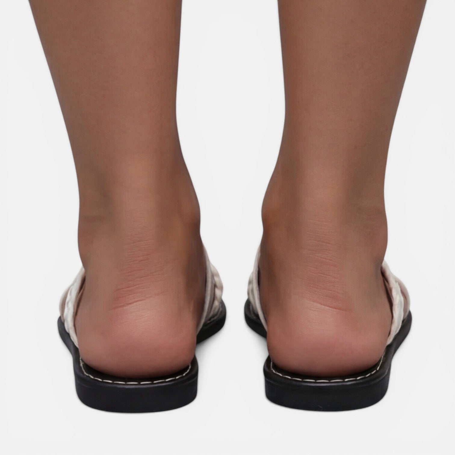 Women’s white flat sandals from the back view with black sole and stitched edge