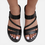 Women’s black leather flat sandals with multiple straps and braided trim around the toe