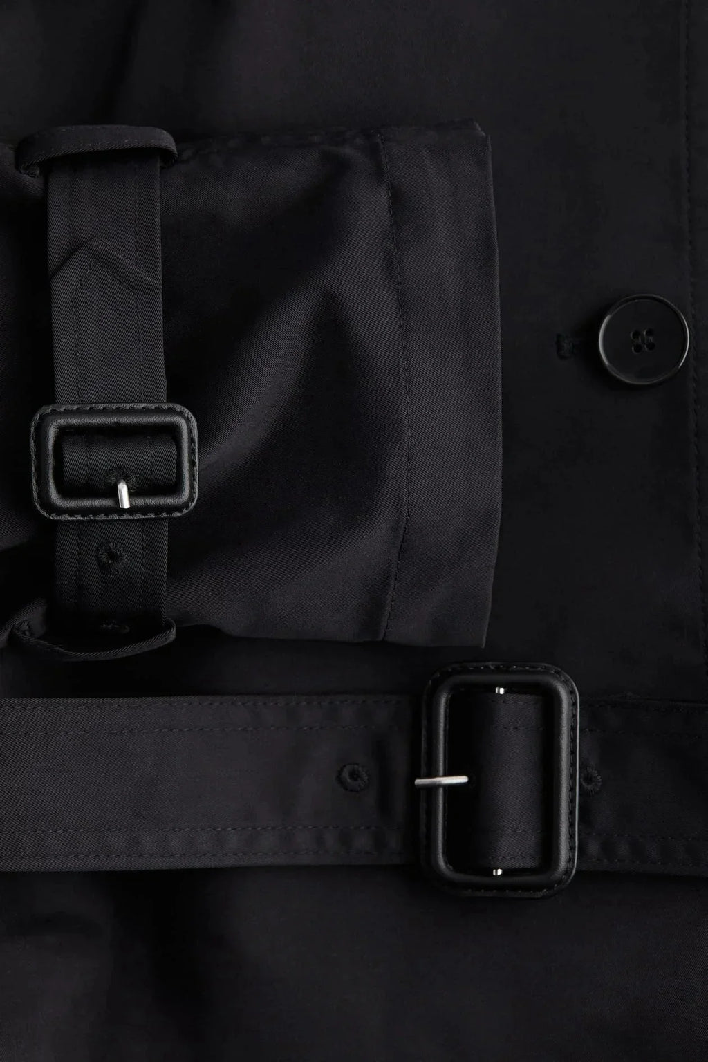 Black trench coat belt detail with stand-up collar and buttoned front