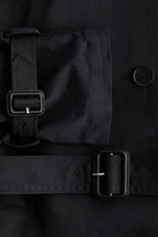 Black trench coat belt detail with stand-up collar and buttoned front